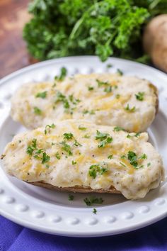 two pieces of bread with cheese and parsley on top sitting on a white plate