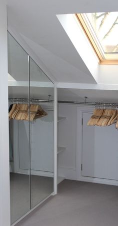 an empty room with some clothes hanging on the racks in front of it and a skylight above