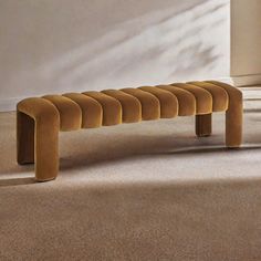 a long bench sitting on top of a carpeted floor next to a white wall