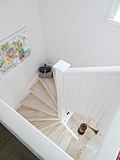 an aerial view of a spiral staircase in a white painted house with wood floors and wooden handrails