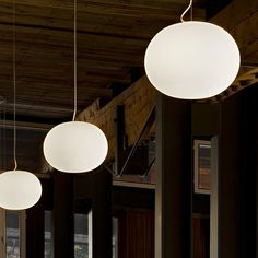 three circular lights hanging from the ceiling in a room with wooden floors and ceilings, along with windows