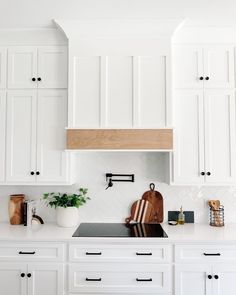 a kitchen with white cabinets and wood accents on the counter tops, along with a cutting board