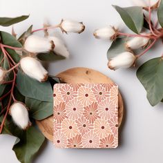 a wooden cutting board sitting on top of a table next to some flowers and leaves