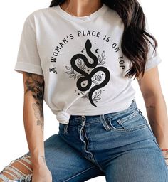 A woman's place is on top graphic tee | feminist shirt | women empowerment tshirt | feminism gift MATERIAL & FEATURES * 100% combed and ring-spun cotton (Heather colors contain polyester) * Pre-shrunk fabric * Side-seamed construction * Shoulder-to-shoulder taping SIZING Please note that majority of the shirts are UNISEX to insure inclusivity and tailor to every beautiful and unique body type. Also please note unisex shirts are longer than women's shirts For the trendy OVERSIZED tee look, consid Ring-spun Cotton Graphic Tee, Relaxed Fit Ring-spun Cotton Tops, Feminist Shirt, Badass Women, Top Graphic Tees, Women's Shirts, Oversized Tee, Unisex Shirts, Shirt Women