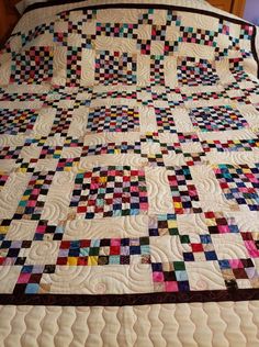 a bed with a large quilt on it's headboard and foot board in the middle