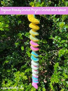 a colorful crochet wind spinner hanging from a tree with the words beginner friendly crochet project wind spinner