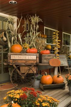 an old wagon filled with pumpkins sitting on top of a wooden porch next to flowers