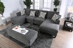 a living room with grey couches and pillows on the floor, coffee table in front of it