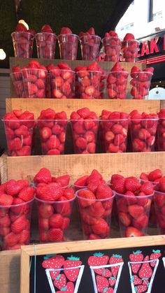 strawberries are arranged in plastic cups on display