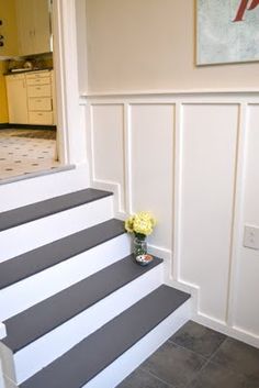 there is a vase with flowers sitting on the stairs in this house's entryway