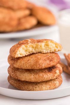 cinnamon sugar cookies stacked on top of each other in front of some cinnamon sticks and a glass of milk