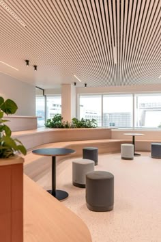 an empty room with round tables and planters