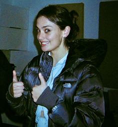 a woman giving the thumbs up sign while wearing a black jacket