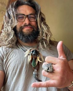 a man with long hair and glasses holding up two rings