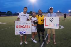 four people standing on a soccer field holding signs