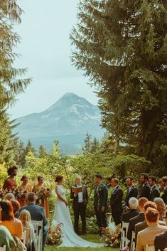 a bride and groom standing at the end of their wedding ceremony in front of a mountain