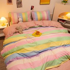 a bed with pink, green, yellow and blue striped comforter on top of it