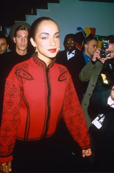 a woman in a red and black outfit is surrounded by people