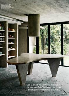 a table in the middle of a room with lots of windows and shelves filled with bottles