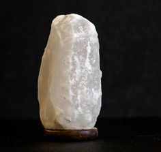 a large white rock sitting on top of a table next to a wooden stand with a black background