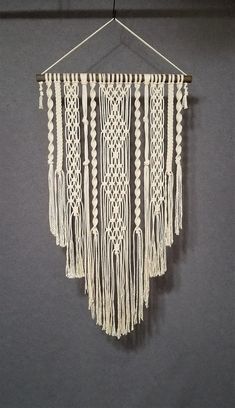 a white macrame hanging on a wall next to a black and gray wall