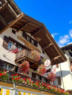 an apartment building with flowers on the balcony and balconies hanging from the roof