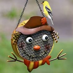 a bird is perched on top of a hanging bird feeder with a scarecrow face