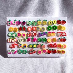 an assortment of fruit and vegetable buttons on a white tray with a white cloth behind it