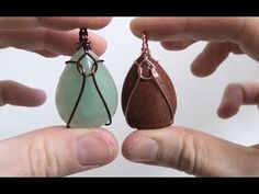 two hands holding small pieces of glass in their palm, one is brown and the other is green