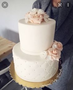 there is a white cake with pink flowers on the top and gold trimmings