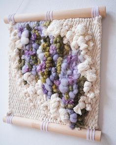 a close up of a wall hanging with yarn and flowers on the inside of it