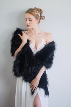 a woman in a white dress is wearing a black feathered shawl over her shoulders