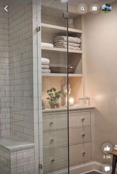 a white bathroom with glass shower doors and shelves