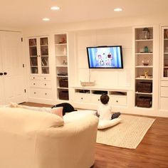 a child sitting on the floor in front of a tv and bookshelves, watching television