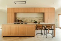 an open kitchen with wooden cabinets and counter tops, along with bar stools in front of the island