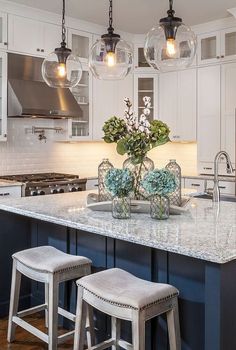 a large kitchen with an island in the middle and two stools at the end