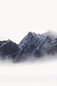 the mountains are covered in snow and fog