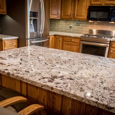 a kitchen with an island in the middle and stainless steel appliances on the other side