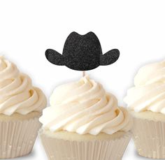 three cupcakes with white frosting and a black cowboy hat on each one