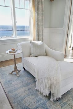 a white couch sitting on top of a rug next to a window