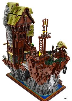 a lego model of a house on top of a rock cliff with a ladder going up the side