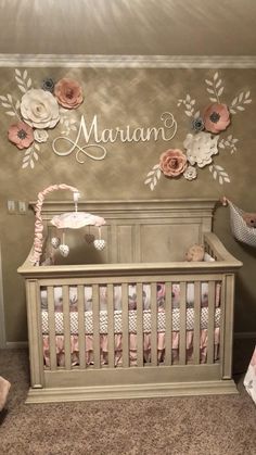 a baby's room with a crib and flowers on the wall