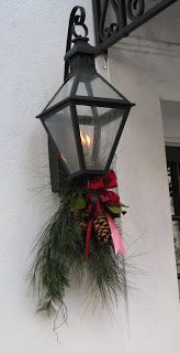 a lantern hanging from the side of a building with a wreath on it and a lit candle