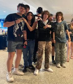 a group of young people standing next to each other in an airport lobby, posing for the camera