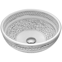 a white bowl shaped sink with an intricate design on the rim and bottom, in front of