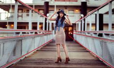 a woman standing on a bridge wearing a hat