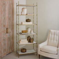 a white chair sitting next to a tall shelf filled with vases and other items