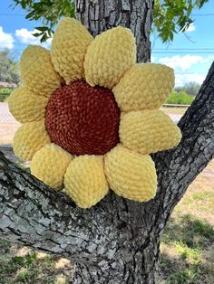 a knitted sunflower sitting on top of a tree