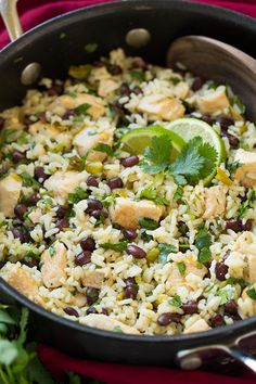 a pan filled with rice, beans and cilantro on top of a table