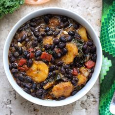 a white bowl filled with black beans and broccoli on top of a table